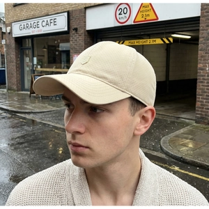 Detail of off-white breathable mesh baseball cap with embroidered shield logo on street