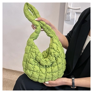 Detail of lime green quilted cloud bag in nylon fabric worn over a black blazer