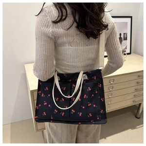 Detail of black cherry print shoulder bag with dual handles and woven white strap
