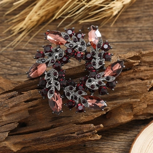 Vintage style red crystal flower brooch with rhinestone leaves on a rustic wood background