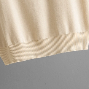Detailed close-up of the ribbed hem on this beige knitted V-neck sleeveless top