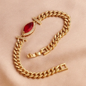 Detail of gold Cuban chain bracelet with red marquise gemstone on champagne silk