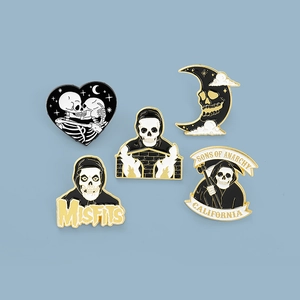 Set kreativer Emaille-Anstecker mit Sensenmann- und Totenkopfmotiven auf blauem Hintergrund