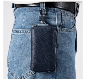 Dettaglio portachiavi in pelle blu scuro appeso al passante di un paio di jeans