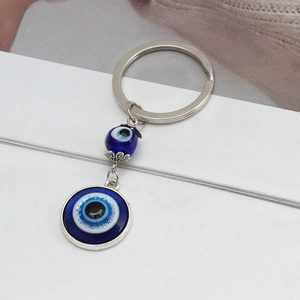 Portachiavi occhio di Allah blu con pendente a piuma d'argento e perla in vetro su bianco