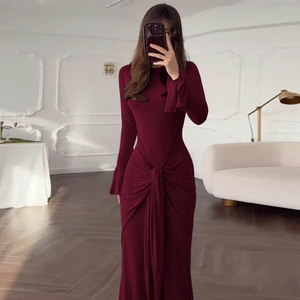 Détail de la robe bordeaux à manches longues avec nœud à la taille et plis