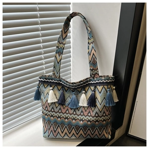 Detail of woven bohemian tote bag with colorful geometric patterns and fringe tassels