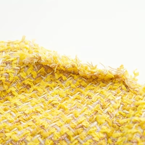 Close-up detail of yellow tweed fabric with woven golden metallic threads and soft chenille