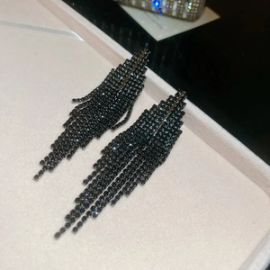 Gros plan d'élégantes boucles d'oreilles à pompons noirs avec strass étincelants