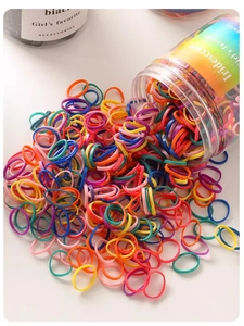 Vista dettagliata di elastici colorati per capelli che escono da un barattolo bianco