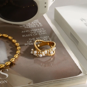 Détail d'une bague dorée avec perles et cristaux sur fond de magazine de mode