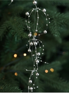 Silver bead garland Christmas ornament hanging on a pine tree branch with bokeh light