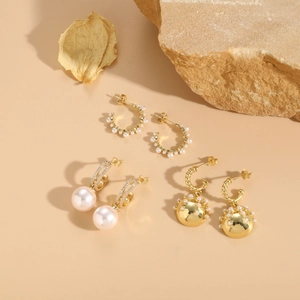 Détails de boucles d'oreilles bohèmes en or avec perles et zircons sur support pierre