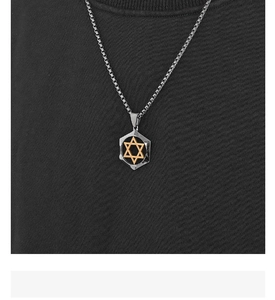 Detail of a black hexagonal pendant with gold Star of David worn on a dark shirt