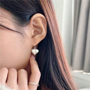 Elegant 925 sterling silver heart earrings with brushed finish on a model's ear