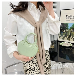 Detail of a mint green heart-shaped jelly handbag worn by a model in a modern indoor setting