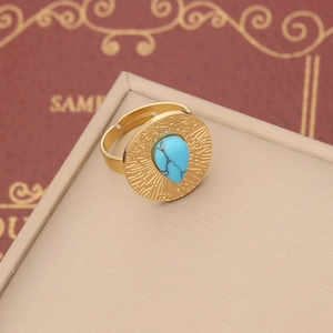 Macro detail of golden bohemian ring with teardrop turquoise and radial sunburst texture