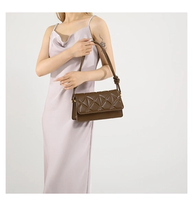 Detail view of dark brown crossbody bag with geometric diamond quilting and knotted strap