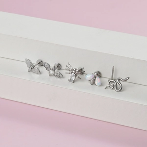 Détail macro de piercings en acier inoxydable avec motifs de chauve-souris, araignée et abeille