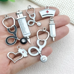 Enamel medical charms including stethoscope, syringe, and nurse hat held in hand
