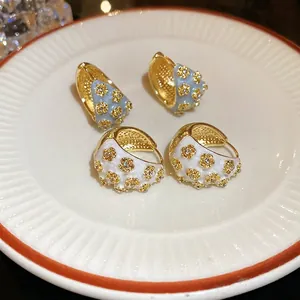 Floral C-shaped hoop earrings with blue and white enamel inlay and sparkly diamonds