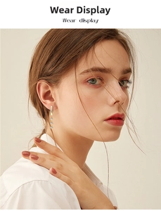 Elegant gold tassel earrings with three clear round stones worn by a model in warm light