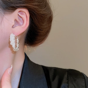 Close-up of silver mesh hoop earring with textured weave pattern worn by a model