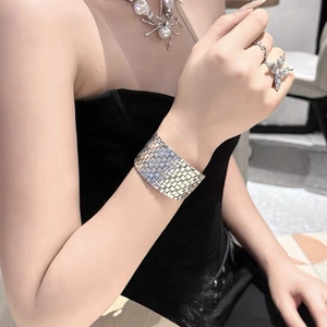 Detail view of silver woven wide metal cuff bracelet styled on a model's wrist