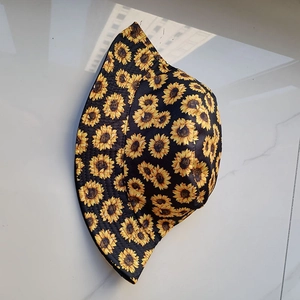Detailed view of sunflower patterns on a black cotton bucket hat for outdoor sun protection