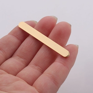Close-up of a hand holding a polished gold stainless steel flat metal bar for DIY jewelry