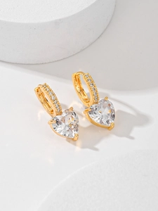 Gros plan de boucles d'oreilles cœur en zircon doré sur un présentoir en pierre