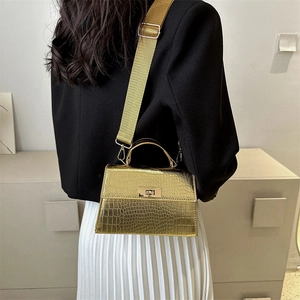 Mini gold crocodile embossed crossbody bag with wide strap worn with chic outfit