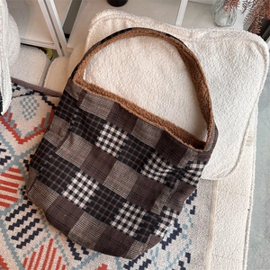 Detail of checkered canvas tote bag with brown faux shearling trim and plush lining