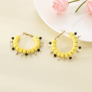 Detail of yellow polymer clay hoop earrings with handmade bohemian beads and gold wire