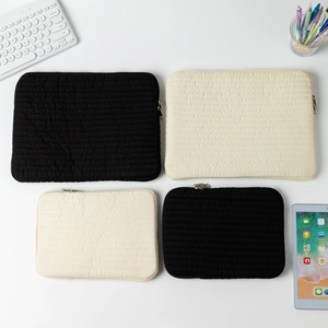 Quilted laptop sleeve in black and off-white with horizontal padded design and top metal zipper