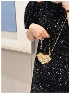 Chic gold lip-shaped metal mini bag with chain strap styled with a black sequin dress