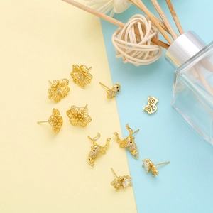 Macro detail of various gold-tone animal earrings featuring bull head and cat designs