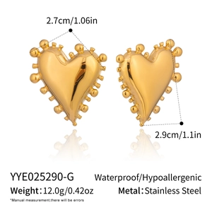Détail macro de boucles d'oreilles cœur géométriques dorées montrant la texture d'acier