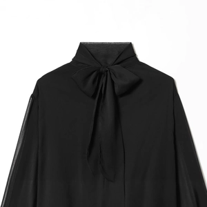 Elegante blusa de gasa negra transparente con cuello alto de lazo y mangas abullonadas