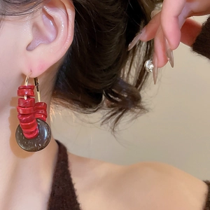 Gros plan de boucles d'oreilles bohèmes avec perles rouges et pendentif en noix de coco