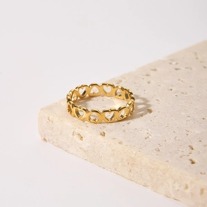 Gold hollow heart pattern stainless steel ring on minimalist stone background