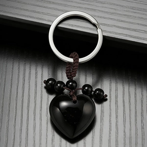 Detailed shot of a heart-shaped black agate pendant with brown braided cord on wood