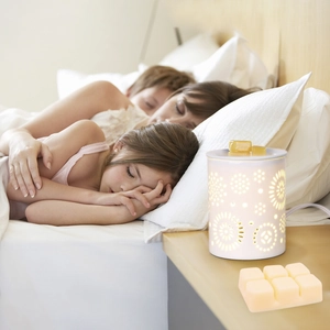 White ceramic wax melt warmer with snowflake cutout and soy wax cubes on nightstand