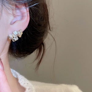 Detail of elegant gold bow earrings with clear zircons and fine brushed metal finish