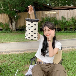 Close-up of a polka dot canvas bucket bag with black lace trim and Korean text label