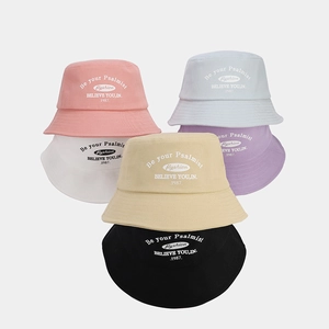 Close-up of stacked cotton bucket hats in pastel colors featuring a retro logo print