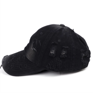 Close-up of distressed vintage black baseball cap with frayed edges and torn details