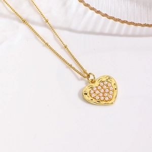 Macro view of a gold plated heart pendant with embedded pearls on a fine bead chain