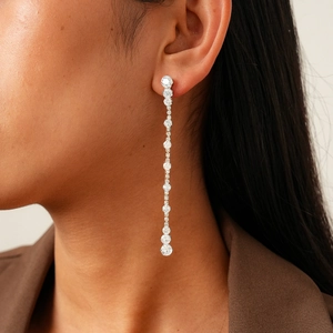 Close-up of long linear silver earrings with cubic zirconia stones worn by a model
