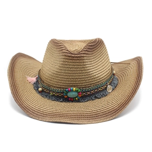 Detail of straw cowboy hat featuring ethnic beads, turquoise stone, and pink tassels